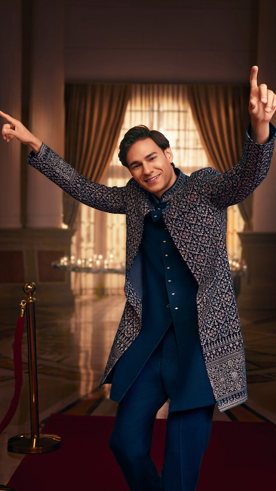 Man wearing a navy embroidered Jodhpuri wedding outfit in a luxury indoor setting